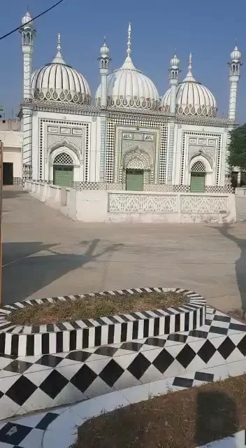 The mosque’s domes and entrance beyond the black and white patterned courtyard.