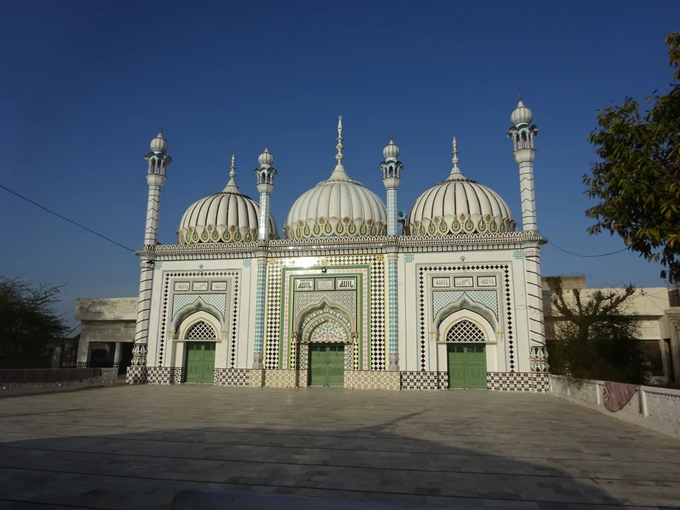 The mosque’s domes and minarets framed by trees beneath a blue sky.